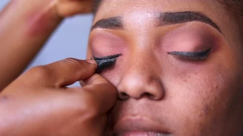 Fixing eye lashes on a woman's eye during makeup	 Stock Footage 217875200