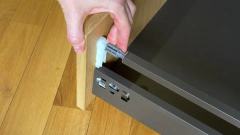 Fixing front end of drawer side rail to wooden front panel close up Stockbeeldmateriaal 333788878