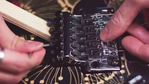 Fixing guitar strings on guitar bridge Stock Footage 118014006