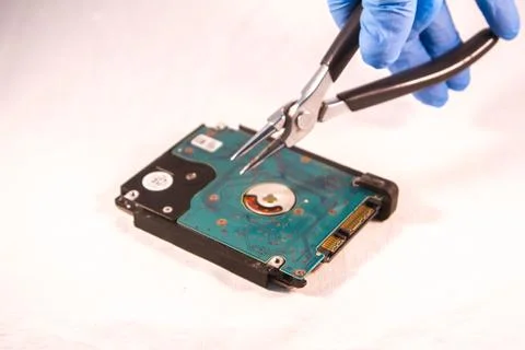 Fixing a hard disk drive with one hand with gloves and a special tweezers Stock Photos