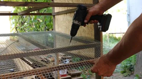 Fixing the mesh in the cage with a screwdriver Stock Photos