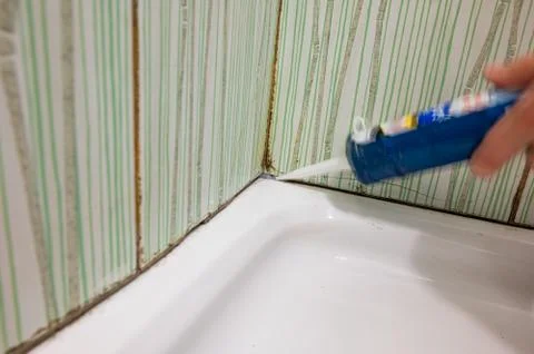 Fixing old mold destroy join lines in bathroom with caulking gun. Stock Photos