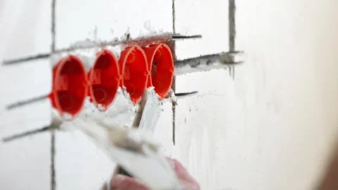 Fixing orange plastic socket box into wall with plaster putty Stock Footage 339298322