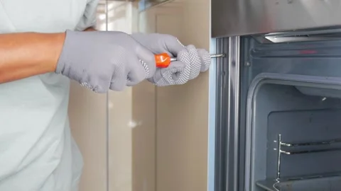 Fixing a refrigerator door with a screwdriver and gloves Stock Footage 341646336