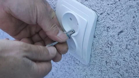 Fixing the socket housing to the wall with a screwdriver Stock Photos