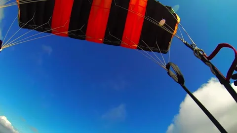 Fixing the straps of black and orange parachute soaring in the air. Stockbeeldmateriaal 230921533