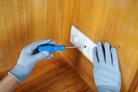 Fixing a wall switch with a screwdriver in a home Stock Photos