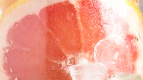 Fizzing water with grapefruit slices and ice cubes in glass, macro. Healthy.. Stock Footage 281269837