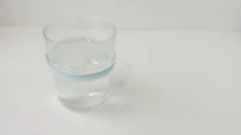 Fizzy effervescent tablet dissolving in a transparent glass of fresh water .. Stock Footage 335141626