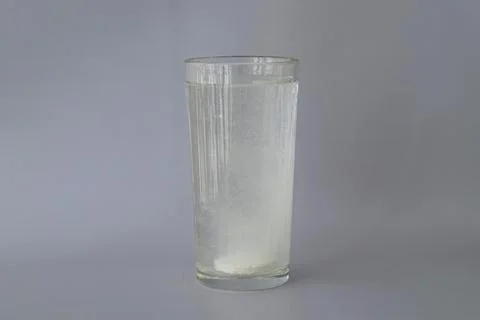 The fizzy round white tablet is dissolved in a glass of water. Supplement Stock Photos