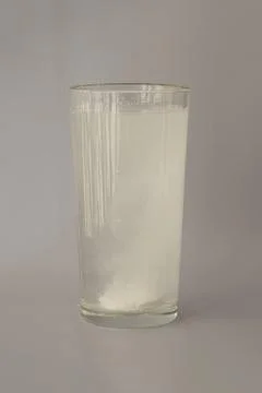 The fizzy round white tablet is dissolved in a glass of water. Supplement Stock Photos