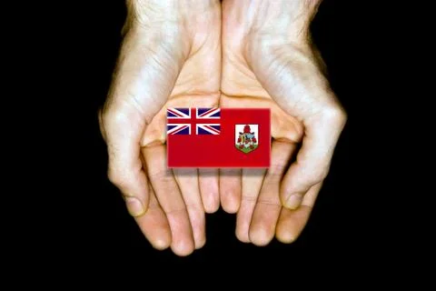 Flag of Bermuda in hands on black background Stock Photos