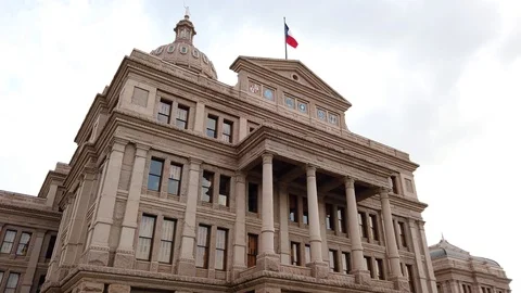 Flag blowing in the wind at The Texas State Capitol Building in Austin Texas 库存影片 107406619