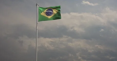 Flag of Brazil billows energetically in the wind against a steely grey sky Stock Footage 240956205