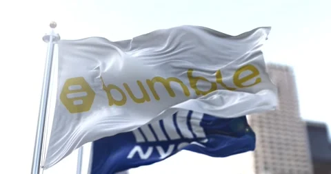 The flag of Bumble dating app flapping in the wind with the NYSE flag Stock Footage 148477310