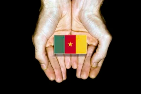 Flag of Cameroon in hands on black background Stock Photos