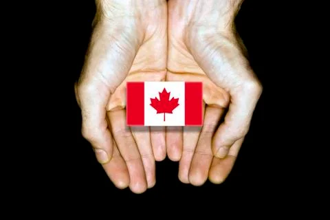 Flag of Canada in hands on black background Stock Photos