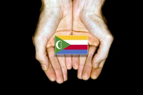 Flag of Comoros in hands on black background Stock Photos