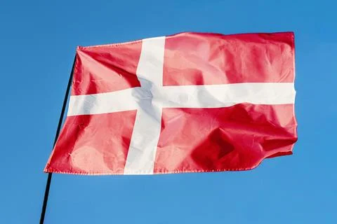 Flag of Denmark. Flag waving in the wind against a clear blue sky, fluttering Stock Photos