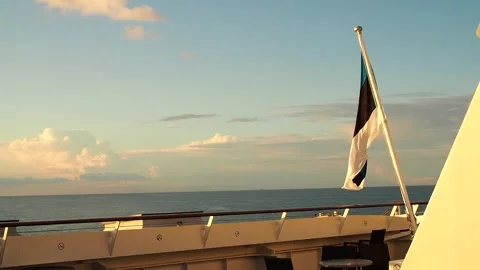 The flag of Estonia flutters in the wind at the stern of a cruise ship at sea. Stock Footage 248531020