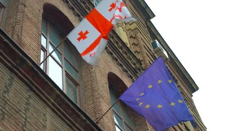  flag of Europe and Georgia is developing in wind against background of building Video stock 113359023