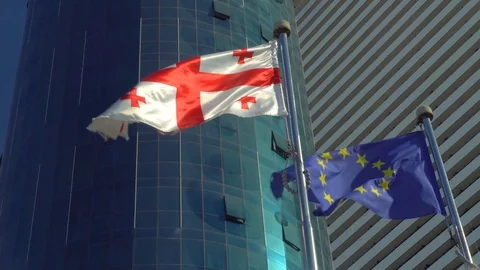 Flag of Europe and Georgia develops against background of  building and sky Stock Footage 114057733