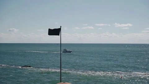 A flag on a flagpole flutters against the background of the sea Stock Footage 168979417