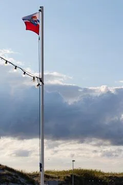 Flag flying against a dramatic sky at a coastal location with soft evening light Stock Photos