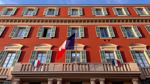 The flag of France waves on the classical facade of the building at sunset Video stock 223027974