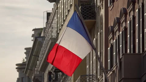 The flag of France waves on the classical facade of the building at sunset Video stock 227361237