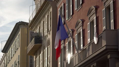The flag of France waves on the classical facade of the building at sunset Video stock 227362587