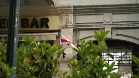 The flag of Georgia is developing in the wind against the background of building Stock Footage 180949389