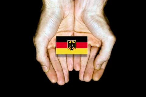 Flag of Germany in hands on black background Stock Photos