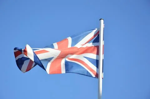 The flag of Great Britain flies in the wind against a blue sky Foto stock