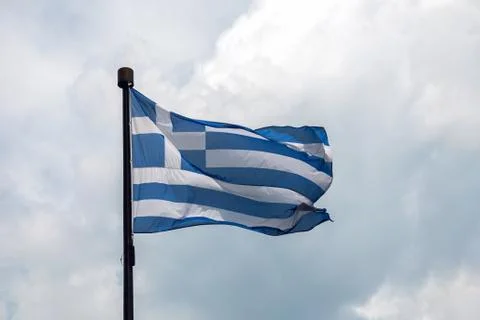 Flag of Greece on flagpole on clouds background Foto stock