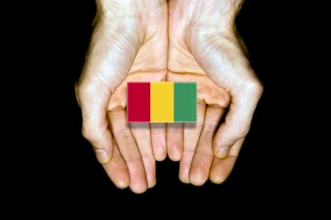 Flag of Guinea in hands on black background Stock Photos
