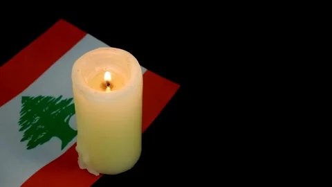 Flag of Lebanon and single burning candle on black background. Stock Footage 288861572