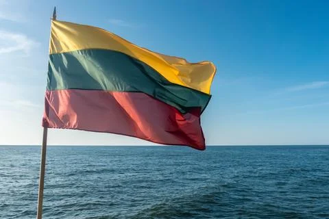 The flag of Lithuania flying in wind over Baltic sea on sky background Stock Photos