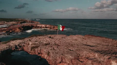Flag of Mexico. Ocean wave hits the cliff in background Stock Footage 233437461