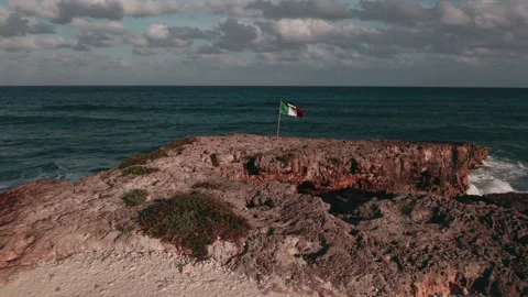 Flag of Mexico. Ocean wave hits the cliff in background Stock Footage 233437510
