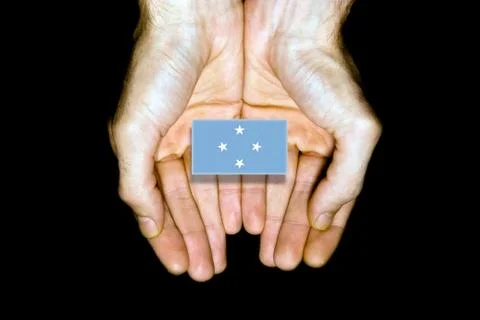 Flag of Micronesia in hands on black background Stock Photos