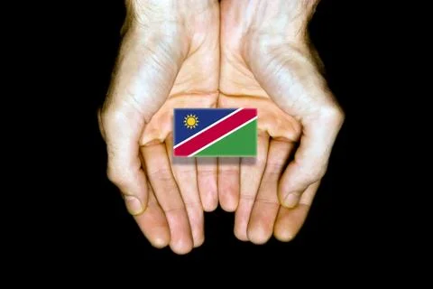 Flag of Namibia in hands on black background Stock Photos