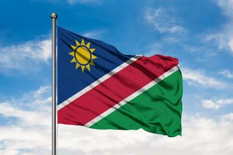 Flag of Namibia waving in the wind against white cloudy blue sky. Namibian fl Stock Photos