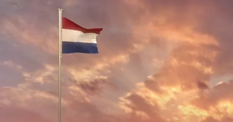 The Flag of Netherlands flies gracefully over a setting sun and its golden rays 動画素材 240956202