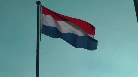 Flag of Netherlands waving slowly on flagpole against clear blue sky 動画素材 343389276