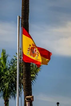 Flag of Spain waving in the wind on flagpole against the sky with clouds on Stock Photos