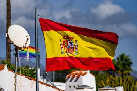 Flag of Spain waving in the wind on flagpole against the sky with clouds on Stock Photos