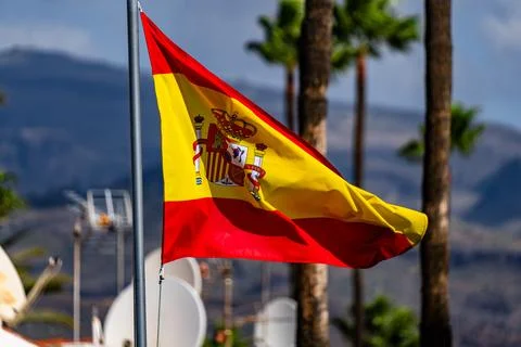 Flag of Spain waving in the wind on flagpole against the sky with clouds on Stock Photos