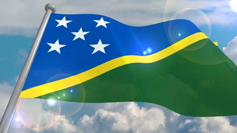 The flag of the state of Solomon Islands develops in the wind against a blue sky Stock Footage 134574780