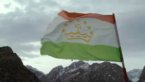 The flag of tajikistan develops in the wind against the background of snow Stock Footage 138870000